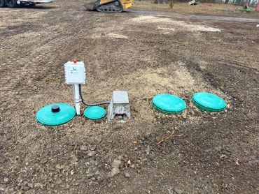 Installed Aeris Aerobics septic system with green lids on a bare soil patch.