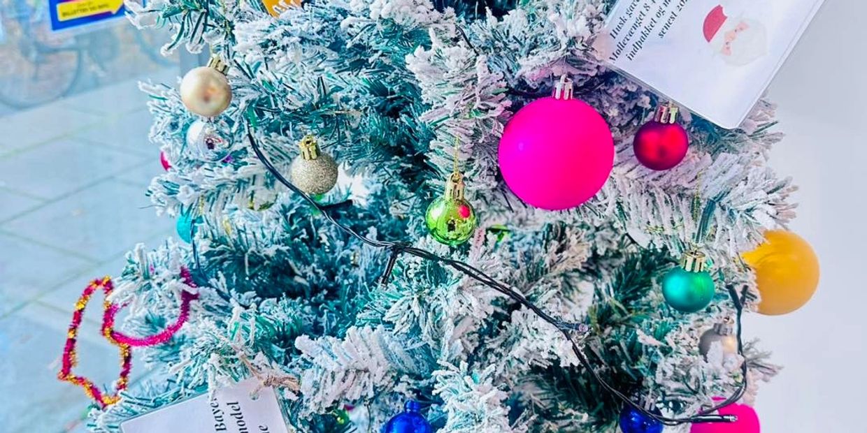 Close-up of a snowy Christmas tree decorated with colorful ornaments and lights.