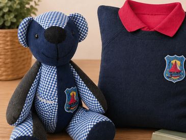 Blue teddy bear and matching shirt with red collar and emblem.