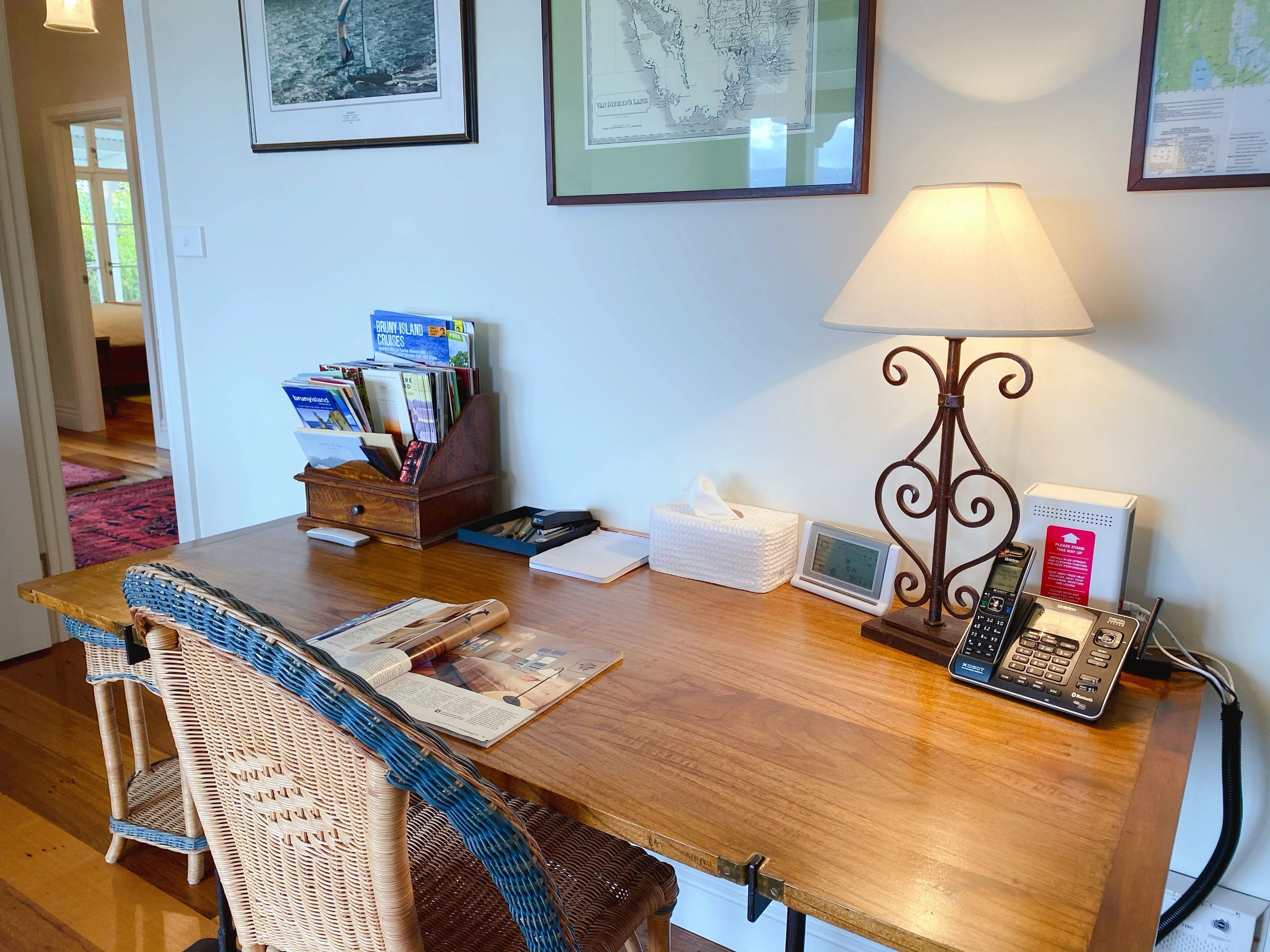 Cozy home office desk with a lamp and wicker chairs.