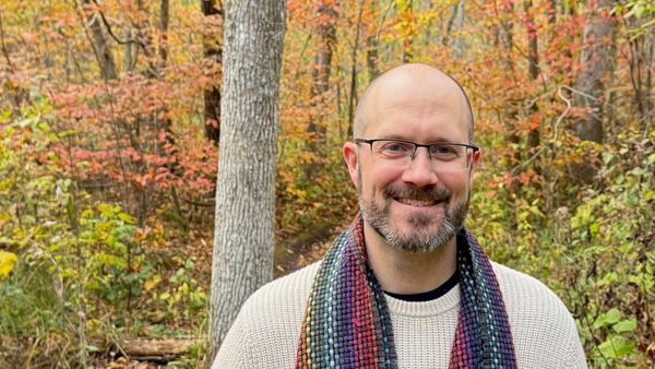 Man standing in the woods surround by fall colors