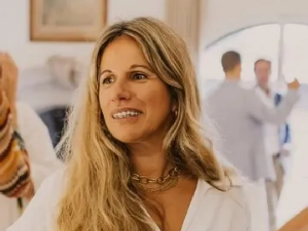 Smiling woman with long blonde hair in a white top at an indoor event.