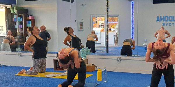 Group of women practicing yoga poses in a studio with mirrors.