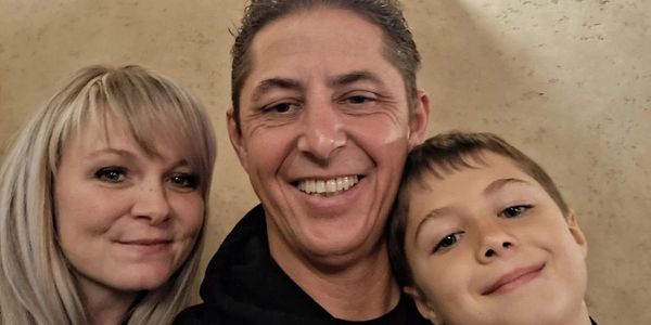 A happy family of three smiling together for a photo indoors.