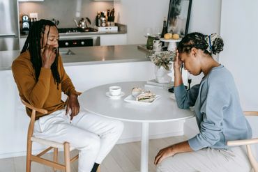 Couple sitting at a table, appearing upset and distant during a meal.
