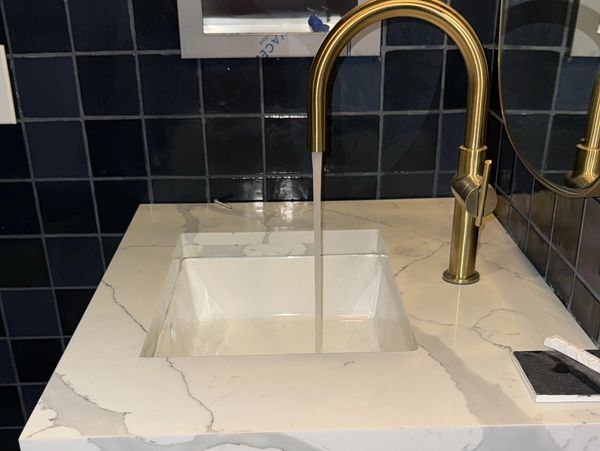 Modern bathroom sink with gold faucet running water.