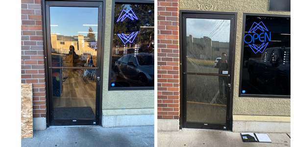 Two storefront doors, one with a neon open sign and cracked glass.