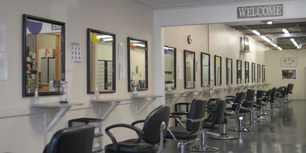 Long row of styling stations with mirrors and chairs in a salon.