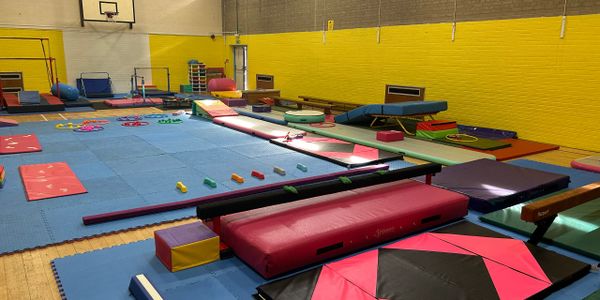 Indoor gymnasium with colorful gymnastics equipment and mats.