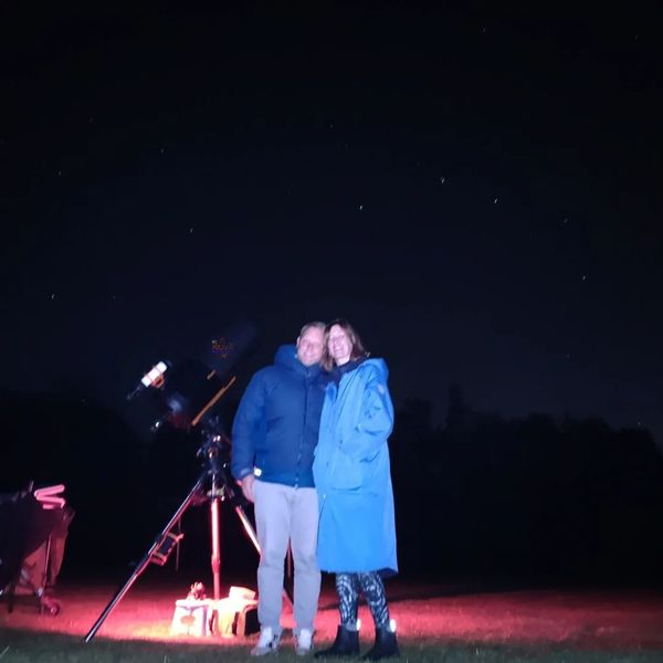 A young couple with NOVA's mobile observatory under the night sky in Oxfordshire