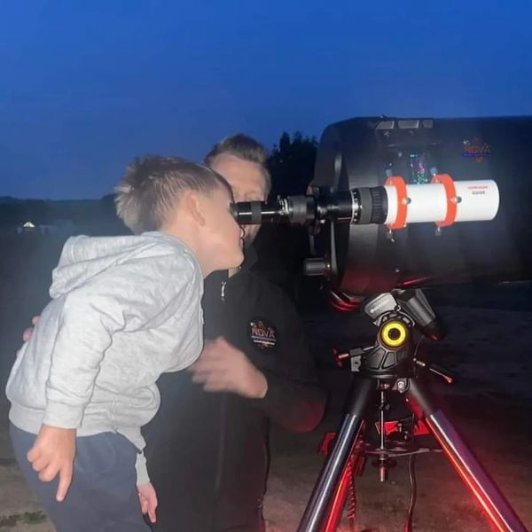 A young boy using NOVA's mobile observatory under the night sky in Bidford on Avon