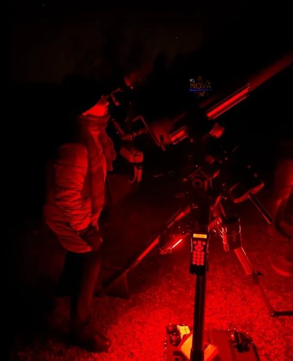 A lady using NOVA's mobile observatory under the night sky in Warwickshire