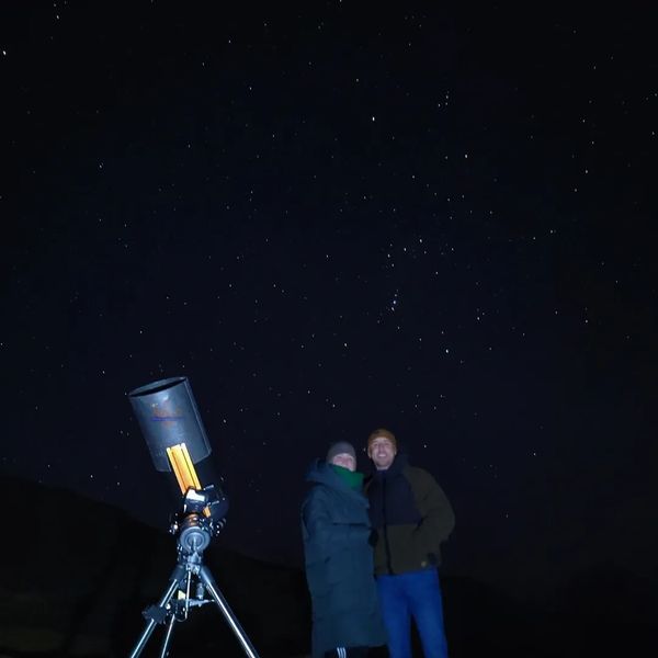 A young couple with NOVA's mobile observatory under the night sky in Wales