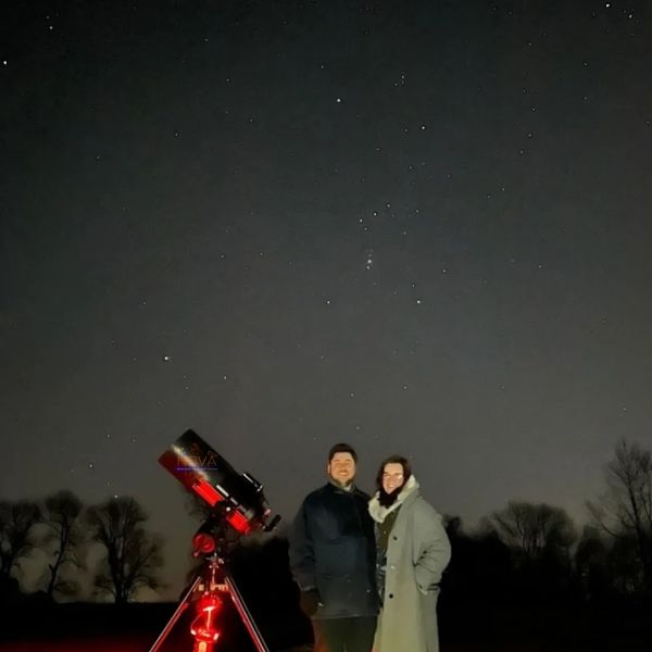 Couple stood next to NOVA's mobile observatory under the night sky in Oxfordshire
