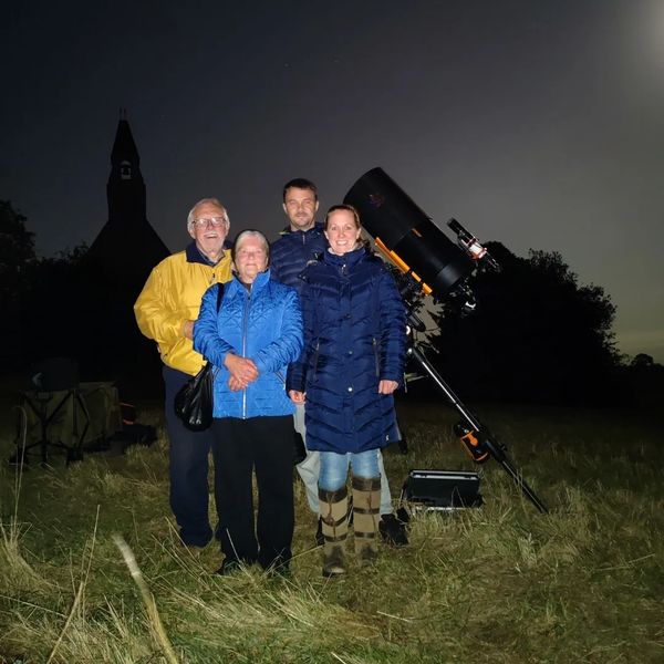 A family of 4 next to NOVA's mobile observatory under the night sky in Warwickshire