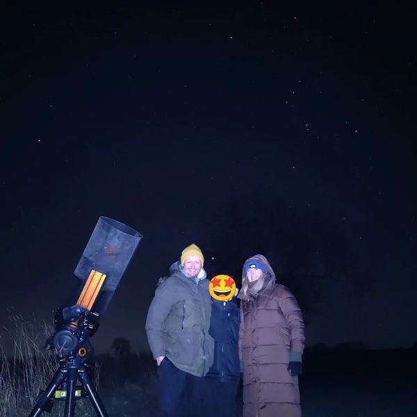 A family stood next to NOVA's mobile observatory under the night sky in Warwickshire