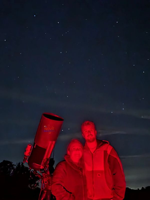 A young couple with NOVA's mobile observatory under the night sky in Oxfordshire