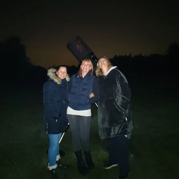 A group of 3 friends with NOVA's mobile observatory under the night sky in Lincolnshire