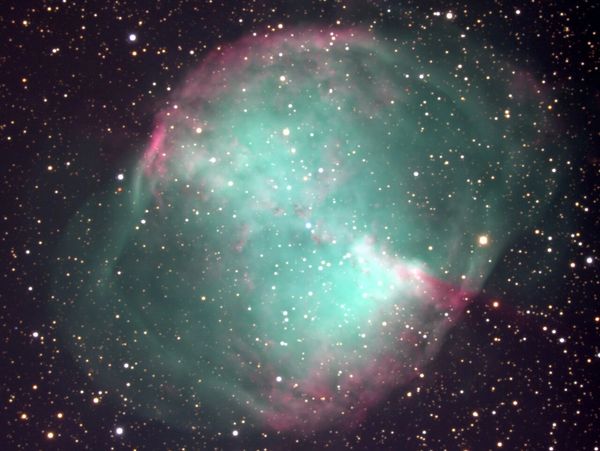 A colorful nebula with green and pink hues surrounded by numerous stars.