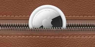 Apple AirTag partially visible in a brown leather zippered pocket.