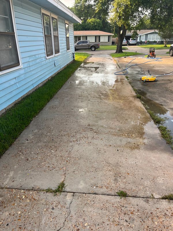 The clean driveway with a yellow surface cleaner and blue hose.