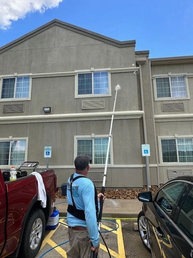 A man using a telescopic wand to soft wash a hotel on a commercial job in Texas City, Texas.