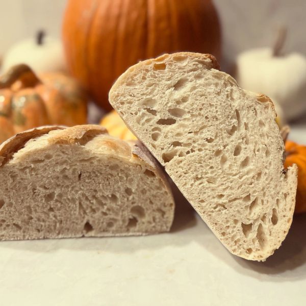 Freshly baked bread halves with pumpkins in the background.