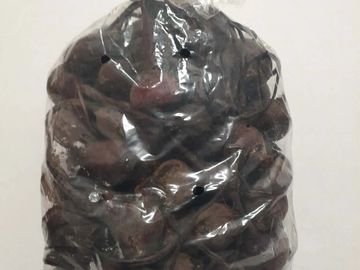 A clear plastic bag filled with dark brown dried tamarind pods.