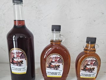Three bottles of Ontario maple syrup in varying sizes on a white surface.