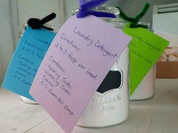 Jars of homemade laundry detergent with colorful tags and usage instructions.