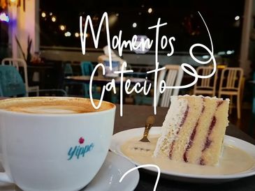 Coffee cup and slice of layered cake on a table in a cozy cafe.