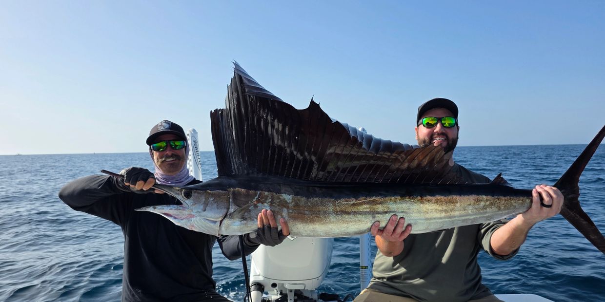 Clients smiling after catching a big sailfish while on a Deep Sea Fishing Trip
