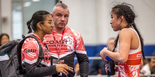 Three people in Coast Wrestling attire having a conversation.