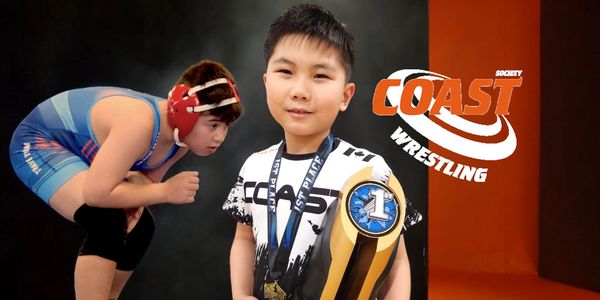 Young boy holding championship trophy with wrestler in background.