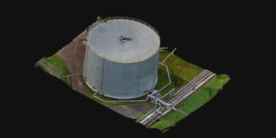Large cylindrical storage tank with connected pipelines on a grassy base.