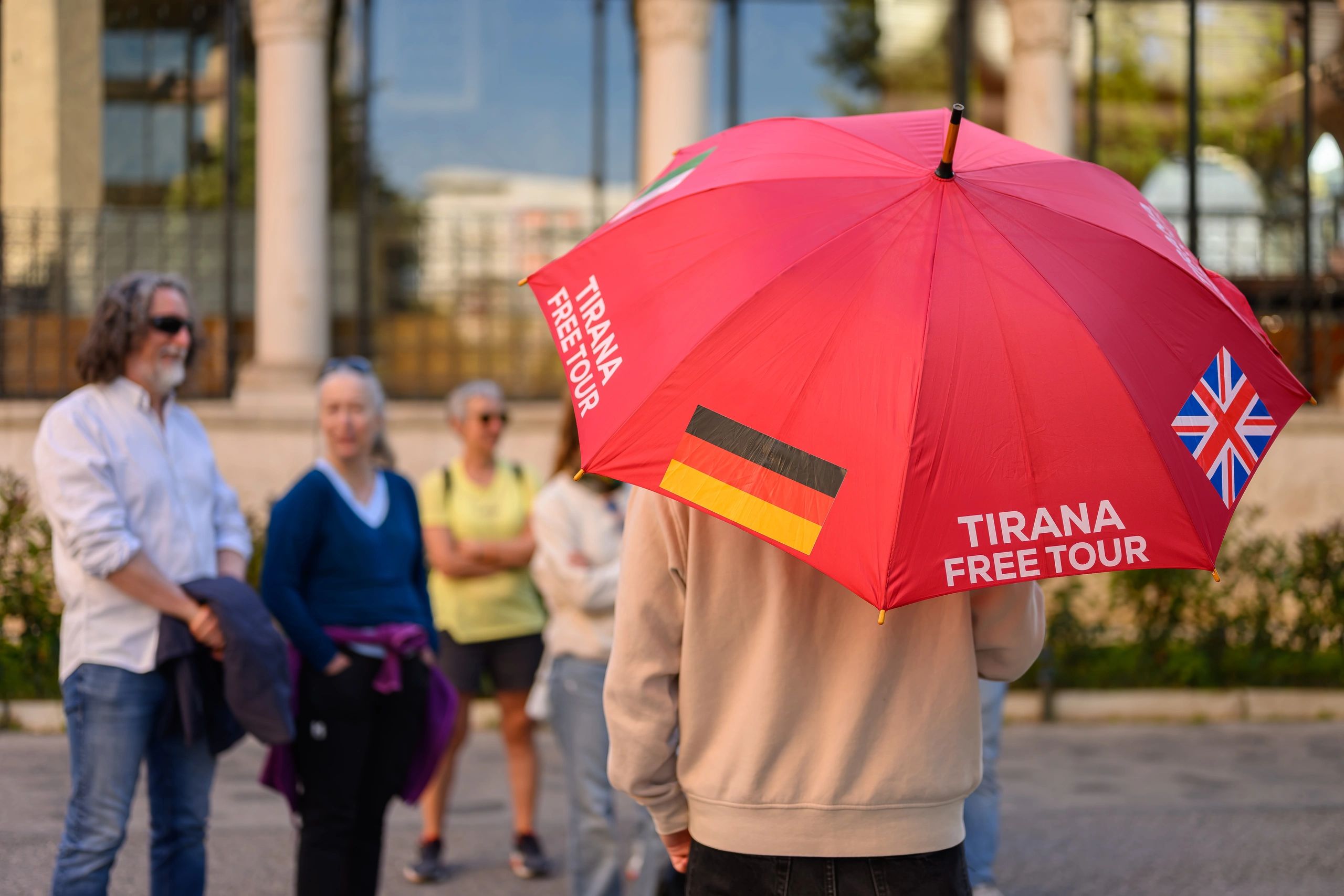Kostenlose Stadtführung Tirana auf Deutsch: Guide mit rotem Schirm bei einer Tour in Albanien