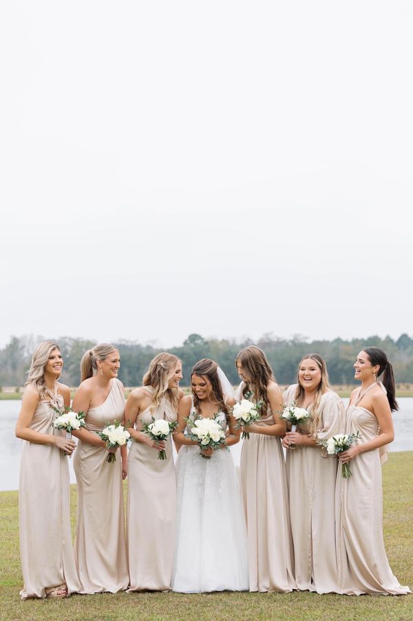 Bridal party with hair styled by Chic & Co. Studio on wedding day posing in front of lake.