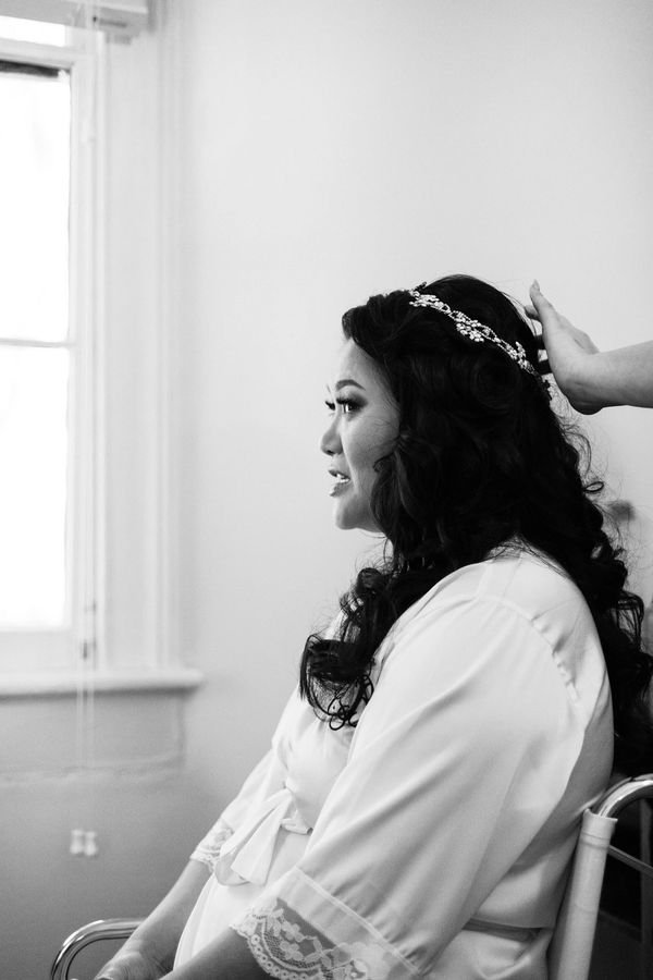 Expert stylist designing hair for bride with dark hair on her wedding day.
