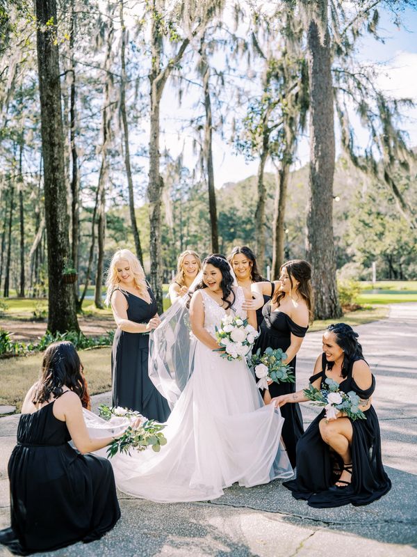 Happy bridesmaids in dark dresses with bride with elegant hair and makeup in Georgia.