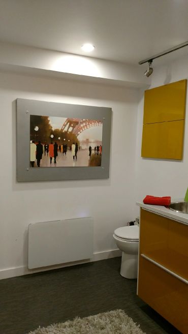 Modern bathroom with yellow cabinets, a painting, and a white toilet.