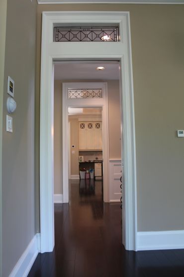 View through multiple doorways into a kitchen with dark wooden floors and beige walls.