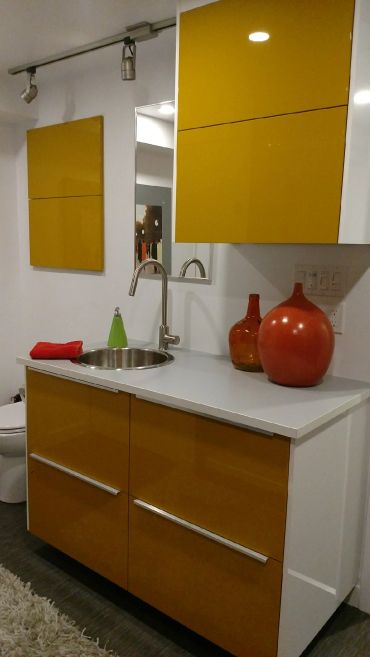 Modern bathroom vanity with yellow cabinets and decorative vases.