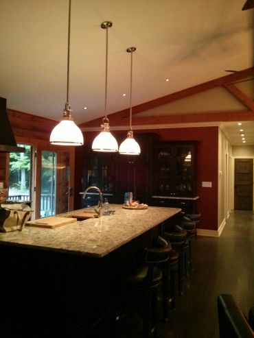 Modern kitchen with granite island and pendant lights.