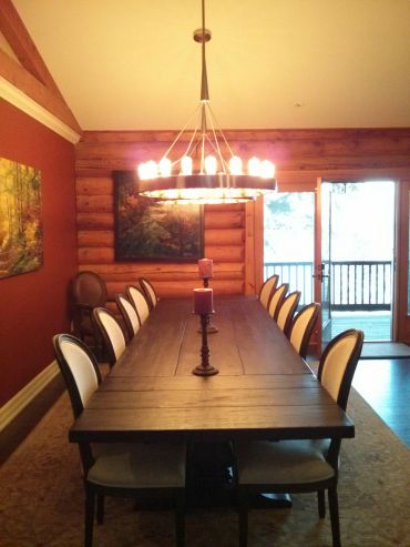 Rustic dining room with a long wooden table and elegant chandelier.