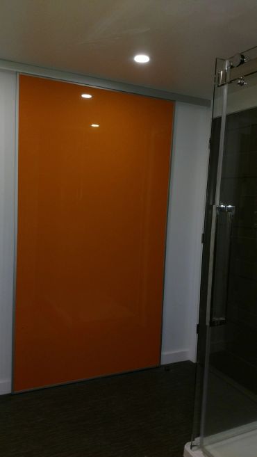 Modern bathroom with a bright orange sliding door and glass shower enclosure.