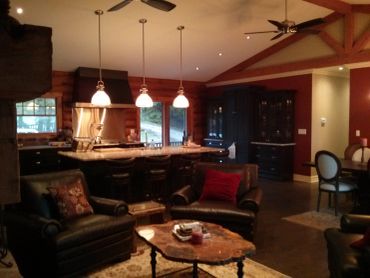 Cozy rustic living room and kitchen with warm lighting and leather seating.