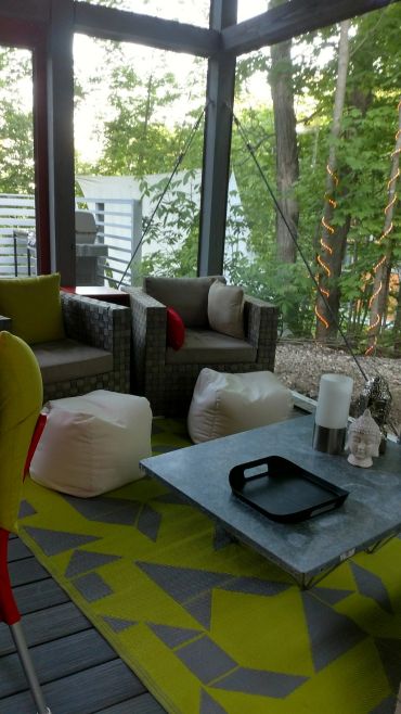Cozy outdoor seating area with cushioned chairs and a geometric rug.