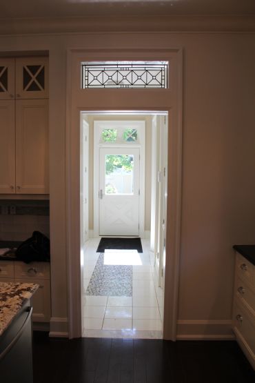 View through a doorway to a bright back door with decorative glass windows.