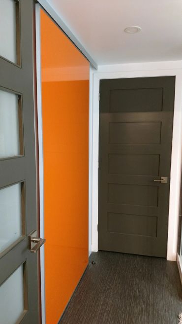 Modern interior with a gray door and an orange sliding door in a hallway.