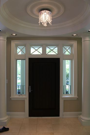 Elegant entrance with a black door, white pillars, and a crystal chandelier.